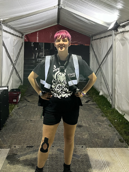 Photo of Jess at ArcTanGent 2024 with her hands on her hips in the entrance to Bixler stage